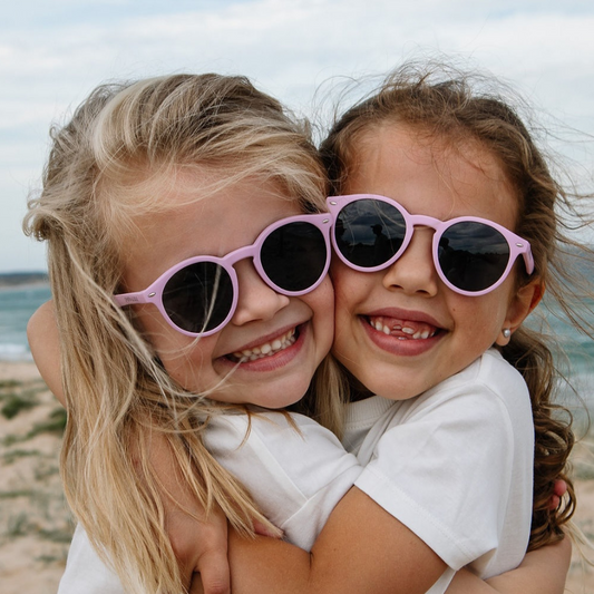 two girls wearing pink uv400 polarised sunglasses on the beach