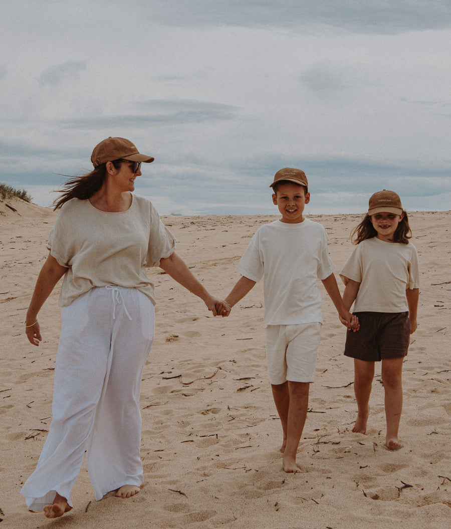 Kara Giovenco founder of Ombra & Sole walking hand in hand with her children Oscar and Scarlett on an Australian beach — a melanoma survivor and mum on a mission to protect families from the sun